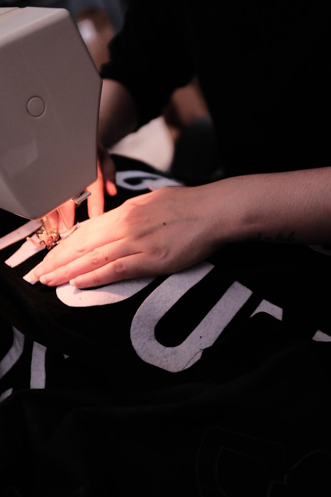 Louise Brooke using a sewing machine on a bespoke velvet banner.