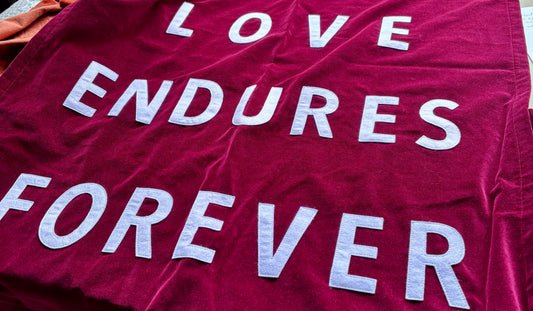 Close up of red velvet banner which reads "Love endures forever"