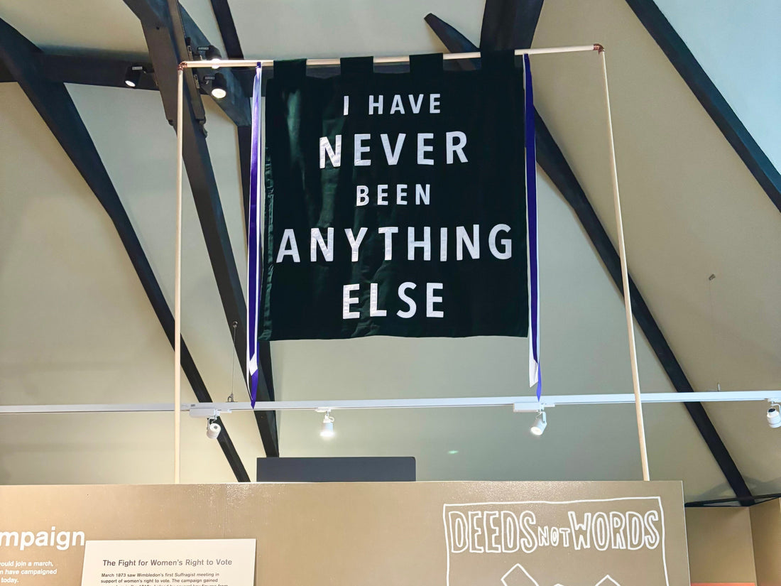 Green velvet banner which reads "I have never been anything else" on a frame in a museum
