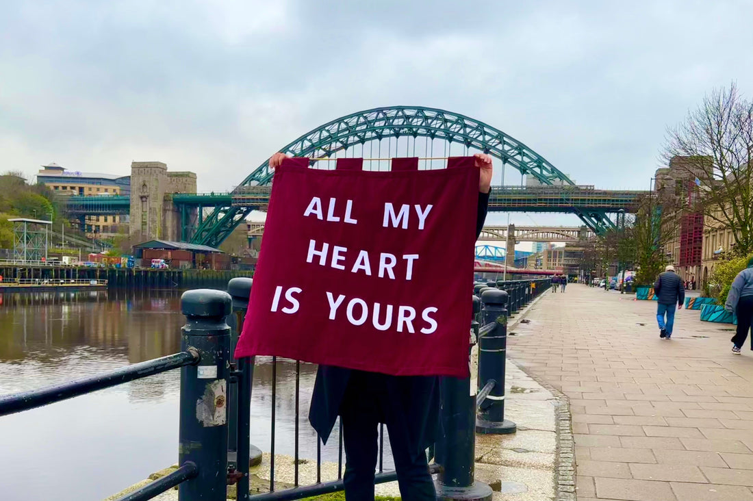 Red velvet banner which reads "ALL MY HEART IS YOURS" in front of the Tyne Bridge in Newcastle