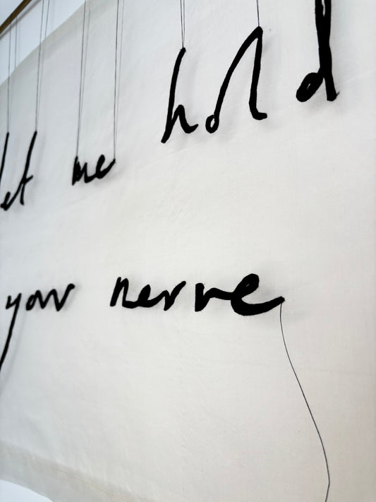 Close up of textile artwork which reads "let me hold your nerve"