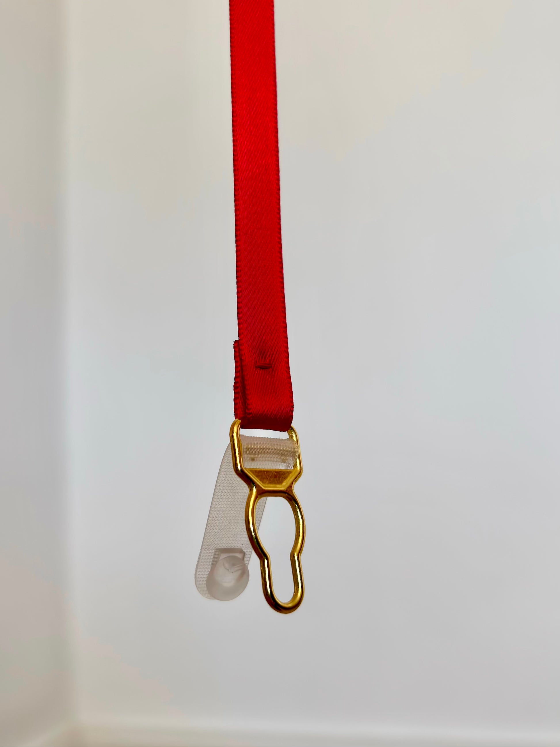 A red ribbon with a gold suspender clasp - left open against a plain white background.