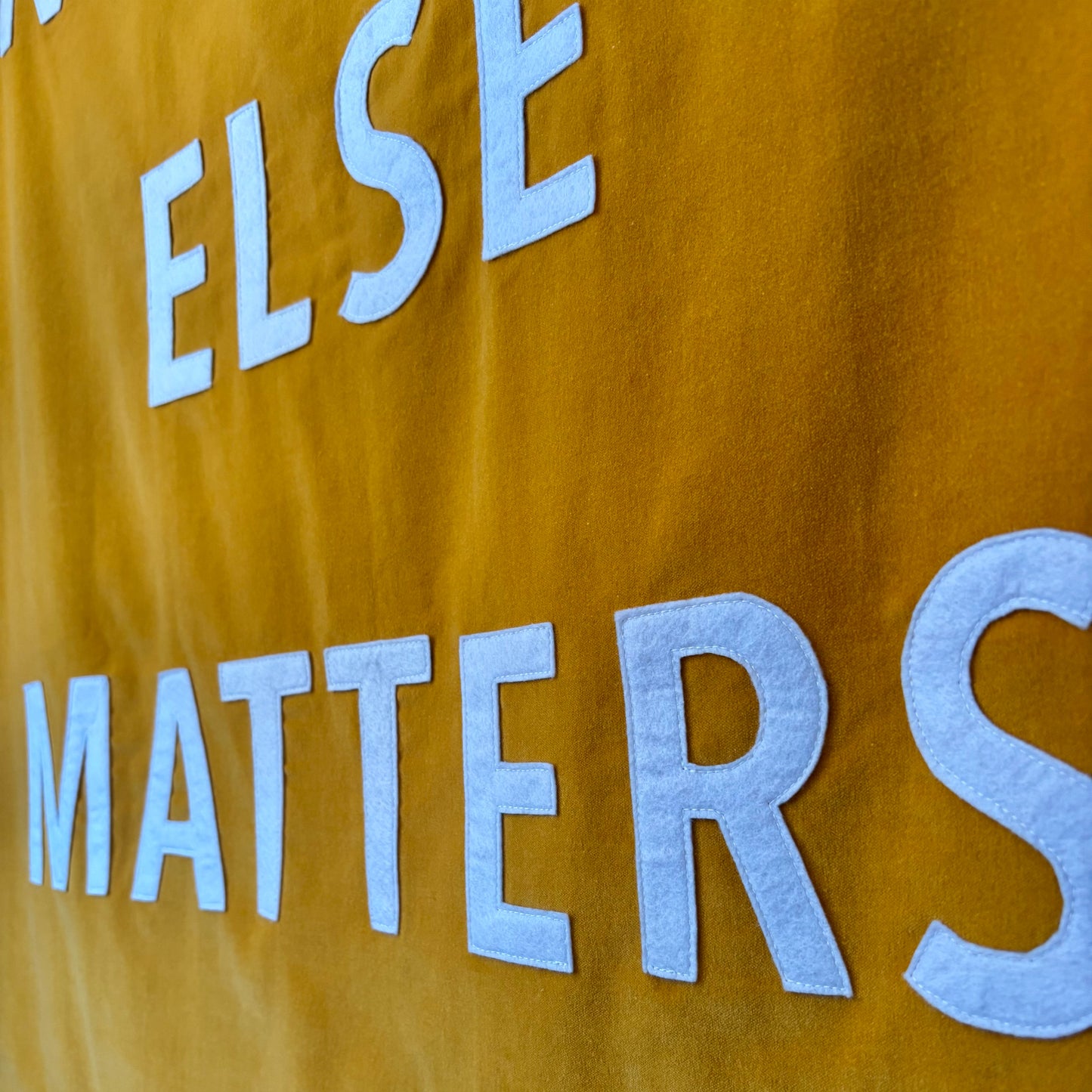 Close up of golden yellow velvet handmade banner with white felt letters.