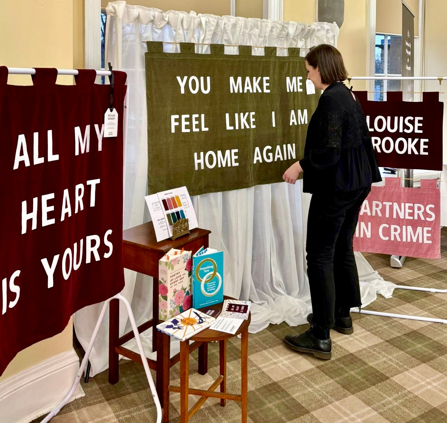 Woman standing next to a wedding fair display with handmade wedding banners and a small table with books