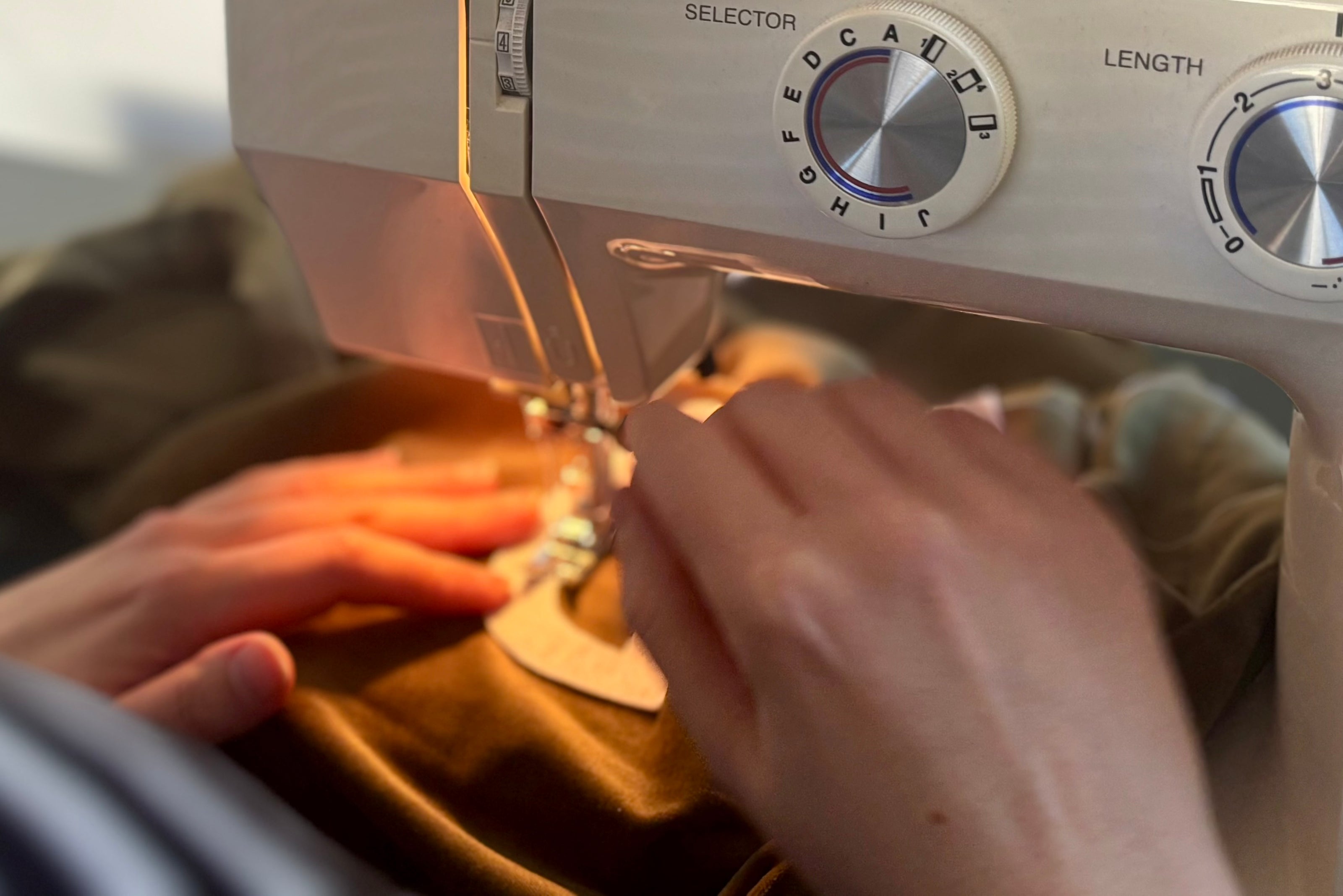 Close-up of a sewing machine with hands operating it