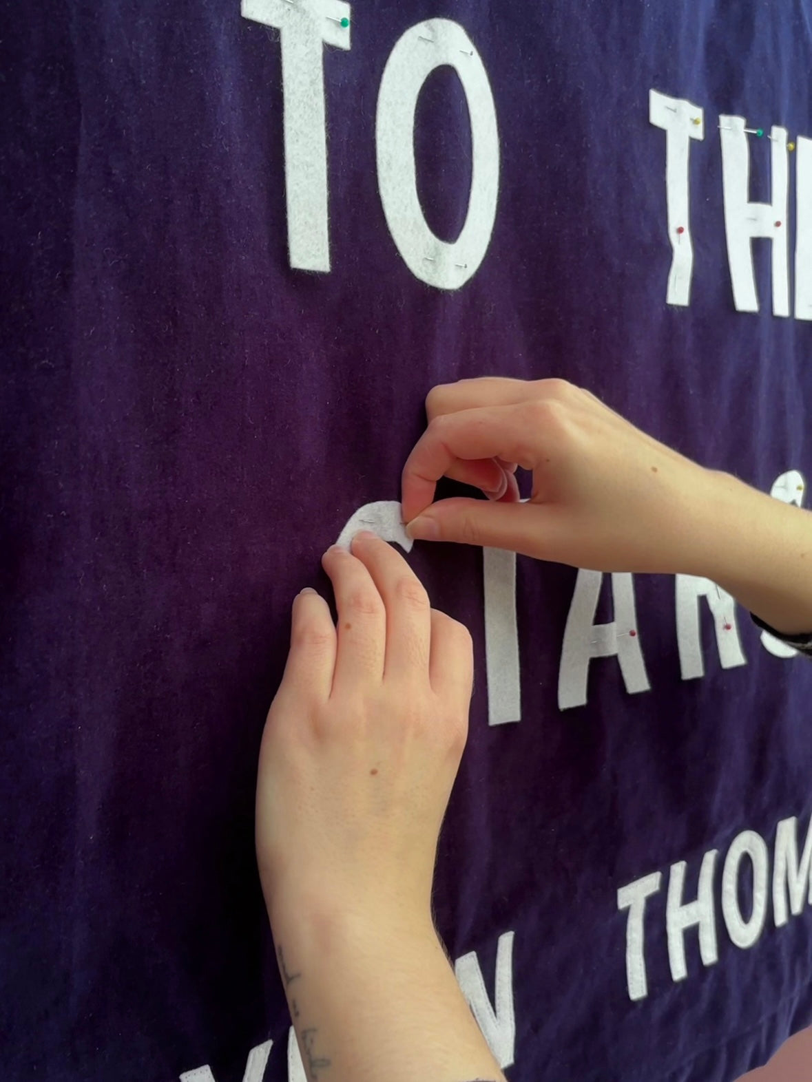 Person pinning white felt letters to a dark blue banner