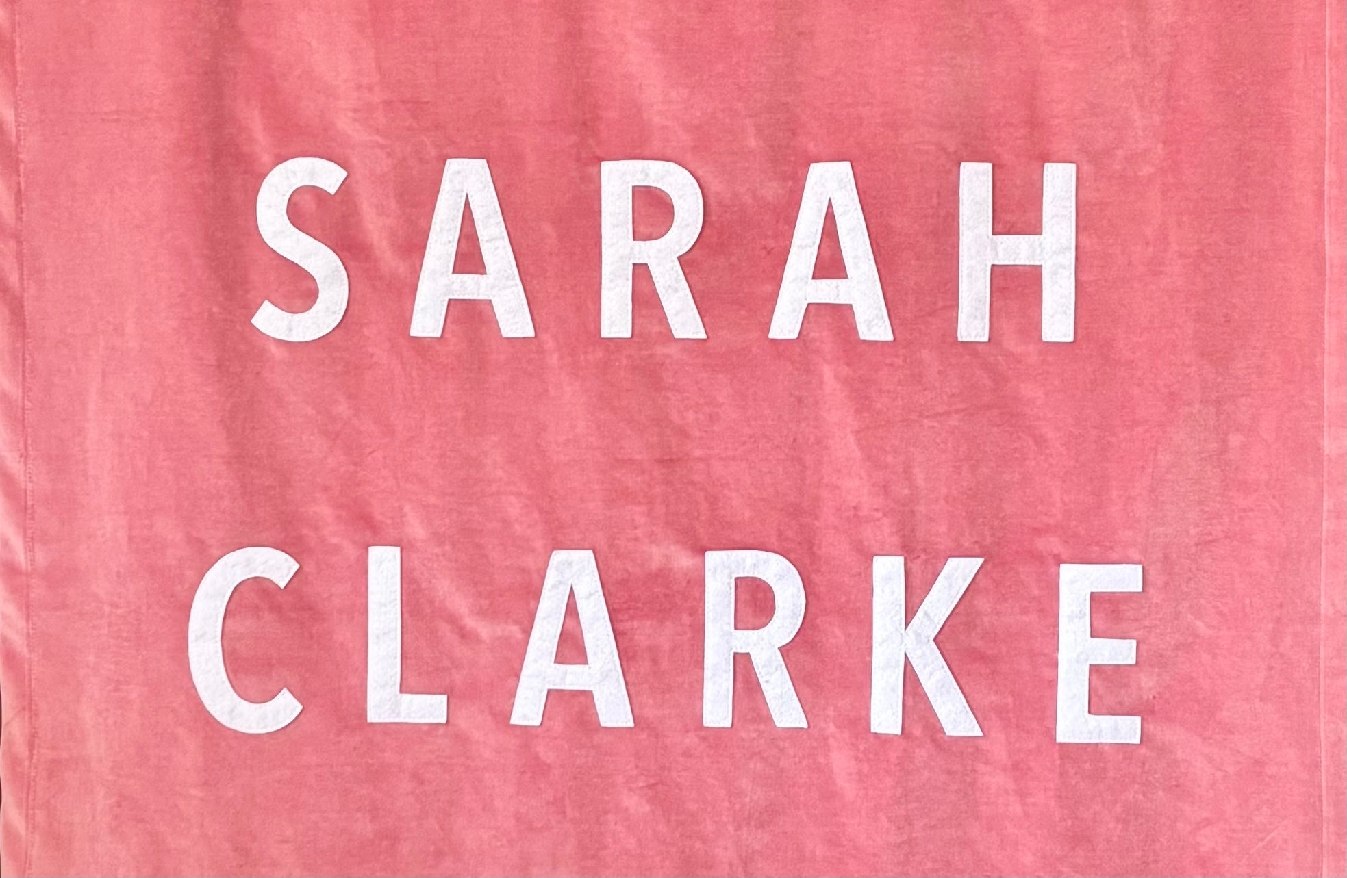 Text 'SARAH CLARKE' on a pink velvet banner.