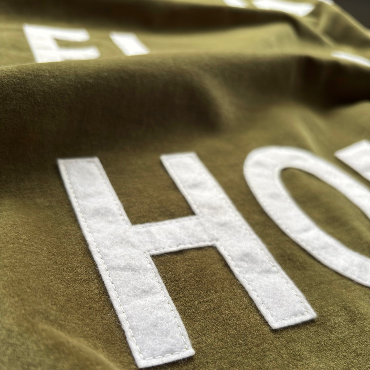Close up of olive green velvet handmade banner with white felt letters.