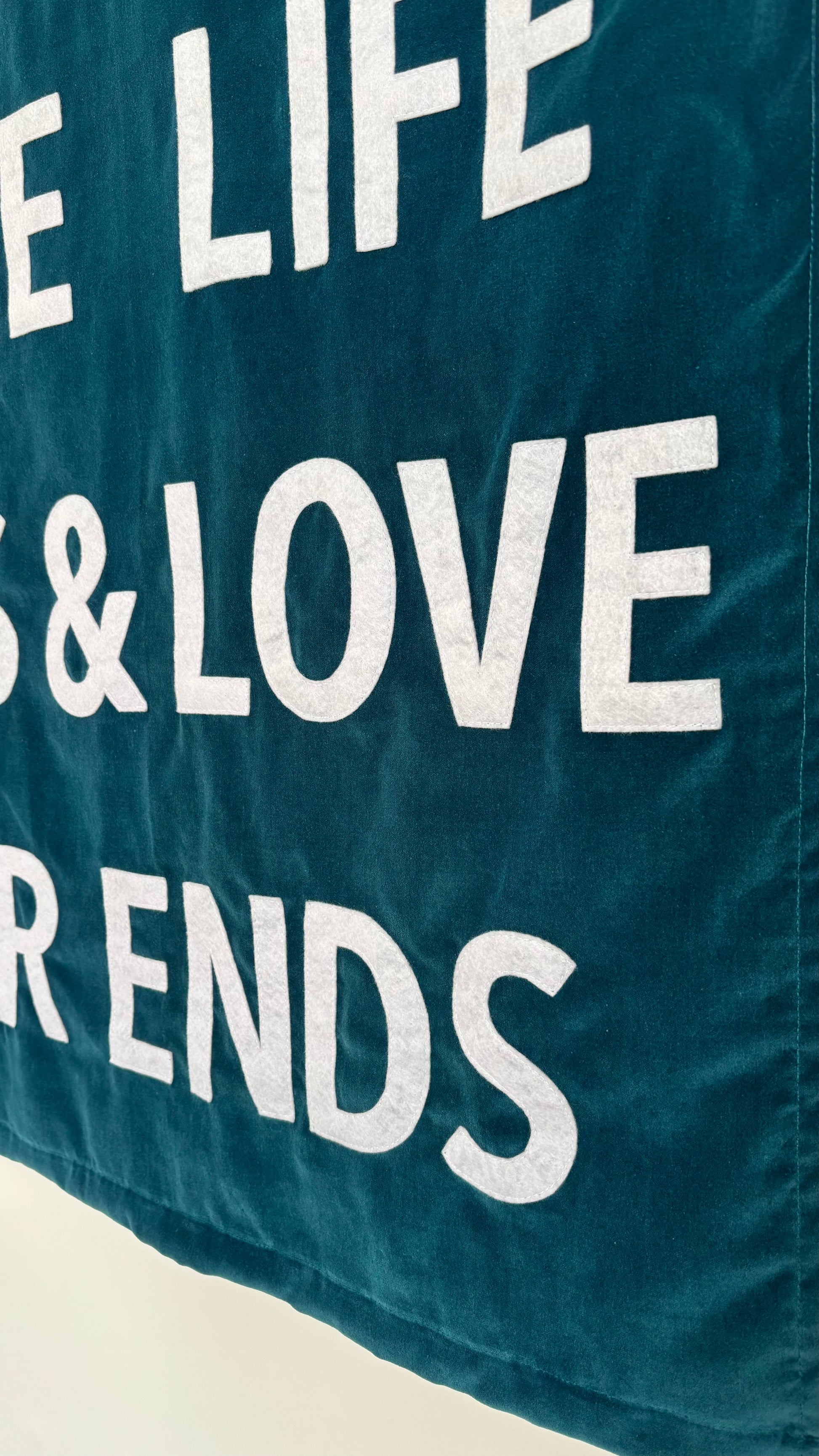 Close up of a teal blue custom velvet banner with "LIFE", "LOVE" white text.