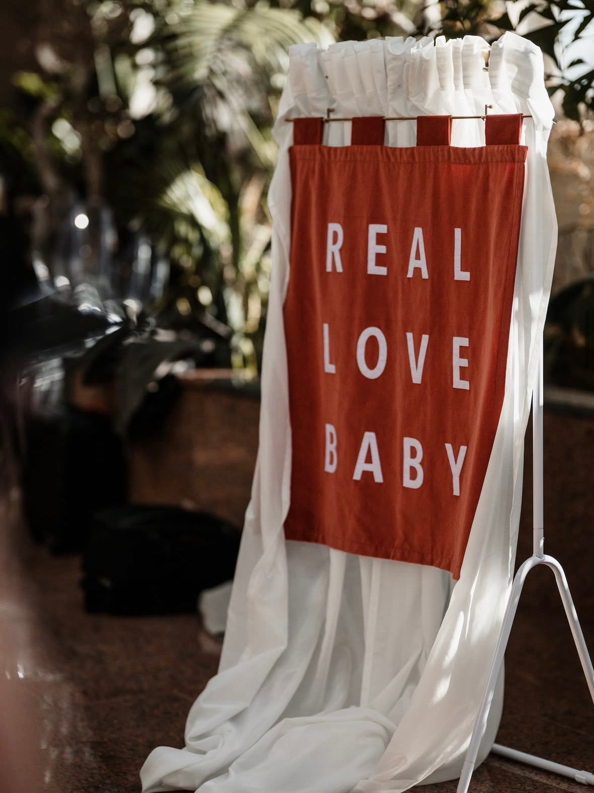 Orange banner with 'REAL LOVE BABY' text draped over a white curtain.