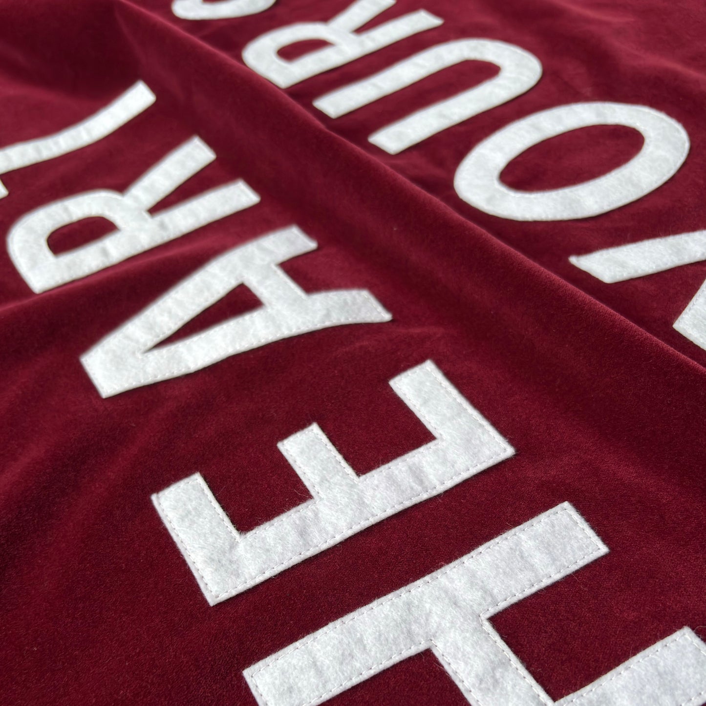 Close up of wine red velvet handmade banner with white felt letters.
