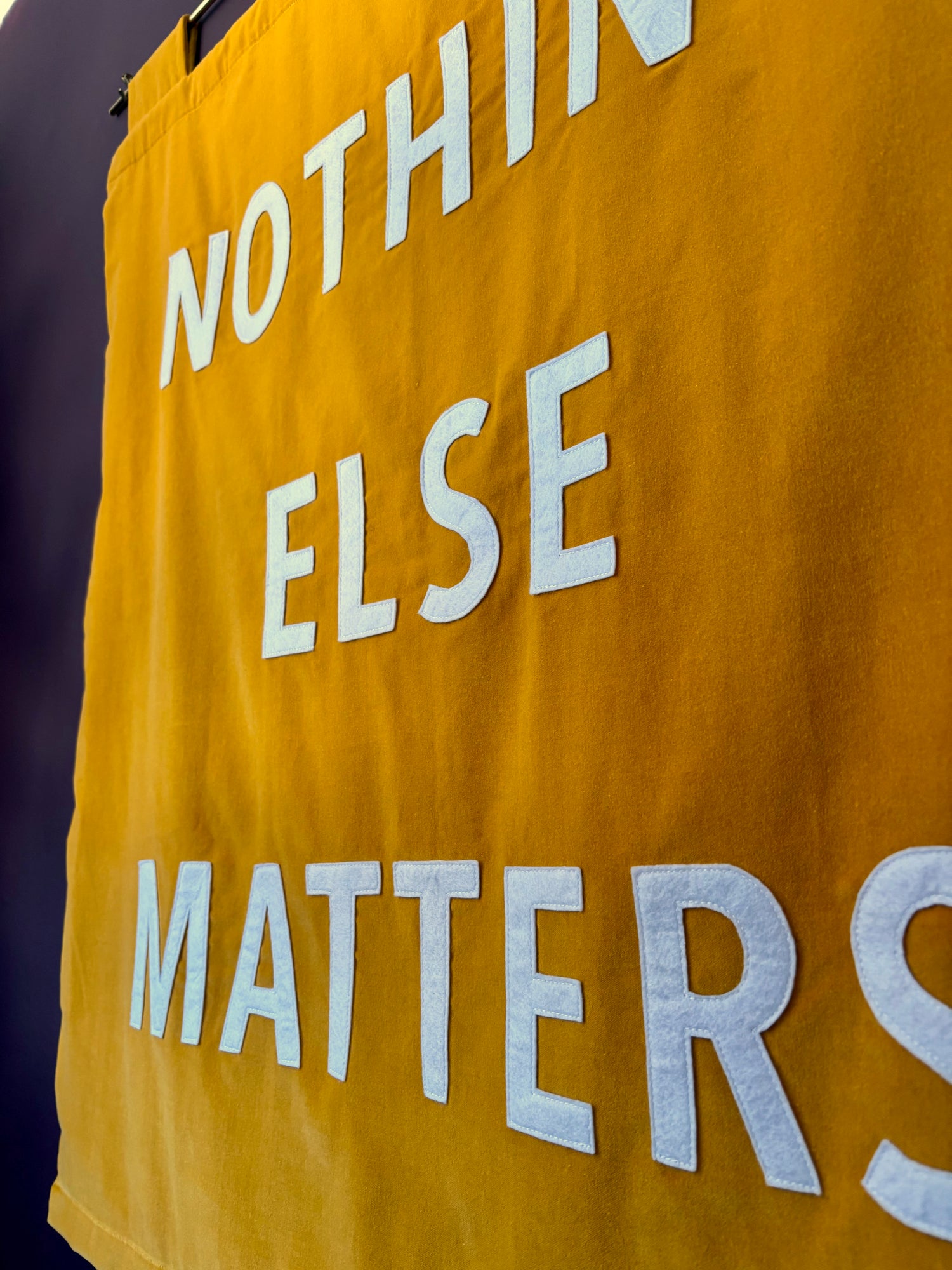 Yellow custom velvet banner with white text 'NOTHING ELSE MATTERS' on a dark background