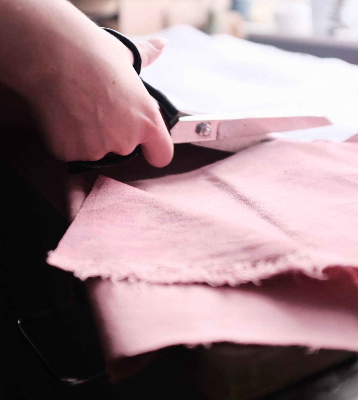 Close-up of artist Louise Brooke's hand cutting pink velvet